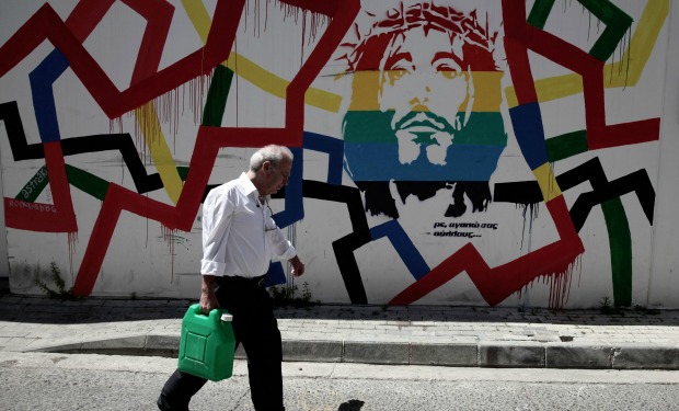 A man walks in front of graffiti bearing an image of Jesus Christ and reading in Greek "I love you all" in Nicosia on May 31, 2014 as the capital readied to host its first Greek Cypriot gay pride parade, 16 years after homosexuality was decriminalised on the Mediterranean island where the influential Orthodox Church views non-heterosexual relations as sinful. AFP PHOTO / YIANNI KOURTOGLOU CYPRUS-GAY-RIGHTS-PEOPLE-CHURCH